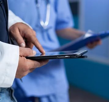 close-up-medic-pointing-tablet-screen-medical-practice-working-late-doctor-using-modern-device-with-touch-screen-talking-assistant-about-healthcare-system-overtime_482257-31856